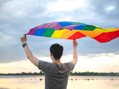 Man holding a rainbow flag over his head.