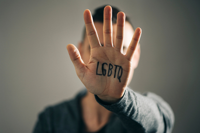 Person holding up their hand marked with LGBTQ.