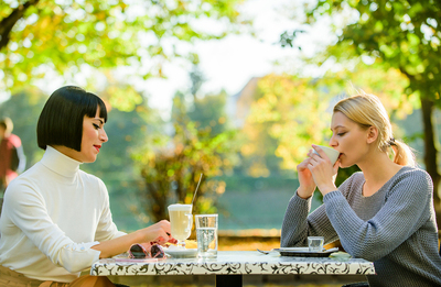 Two women sitting at a dinner table drinking coffee.