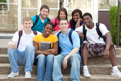 Group of young adults sitting on steps with backpacks.