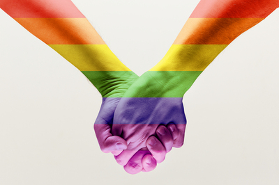 Two people holding hands that are rainbow colored.