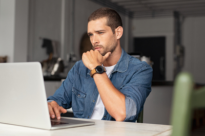 Man looking intently at his laptop screen.