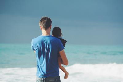 Father carrying a child on the beach.