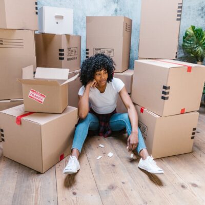 Woman sitting on the floor surrounded by cardboard moving boxes